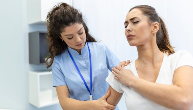 Woman doctor osteopath in medical uniform fixing woman patients shoulder and back joints in manual therapy clinic during visit. Professional osteopath during work with patient concept
