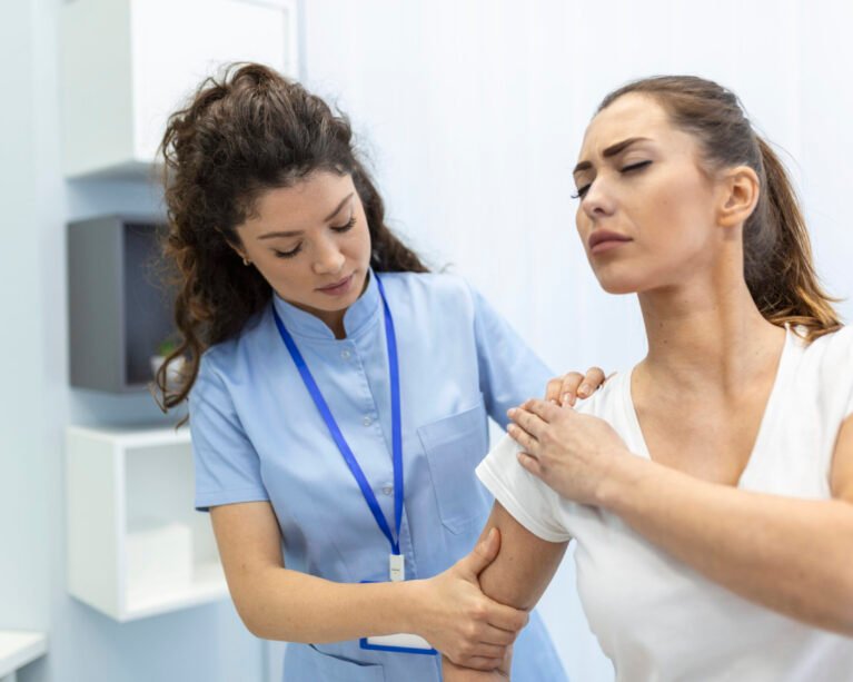 Woman doctor osteopath in medical uniform fixing woman patients shoulder and back joints in manual therapy clinic during visit. Professional osteopath during work with patient concept